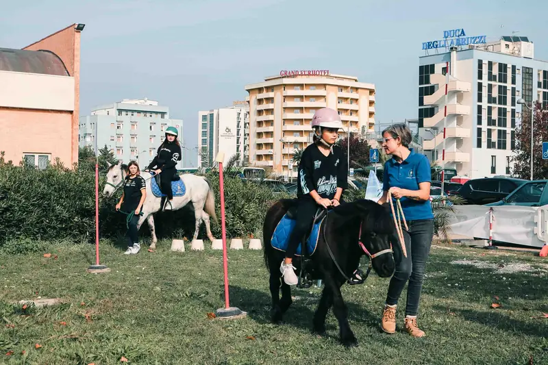 Bambini provano l'equitazione con i pony nell'area esterna